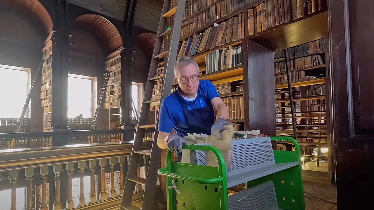 person placing old books on a library cart