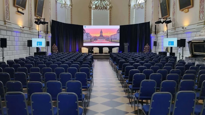 presentation on a large screen in front of chairs at trinity college exam hall