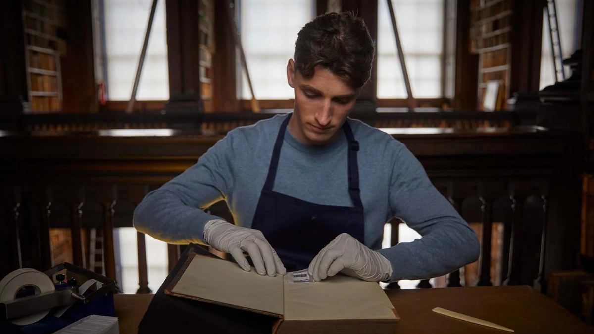 man adding a label to an old book wearing gloves
