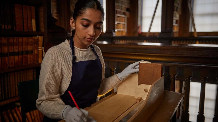 woman using a tool and paintbrush to preserve an old book