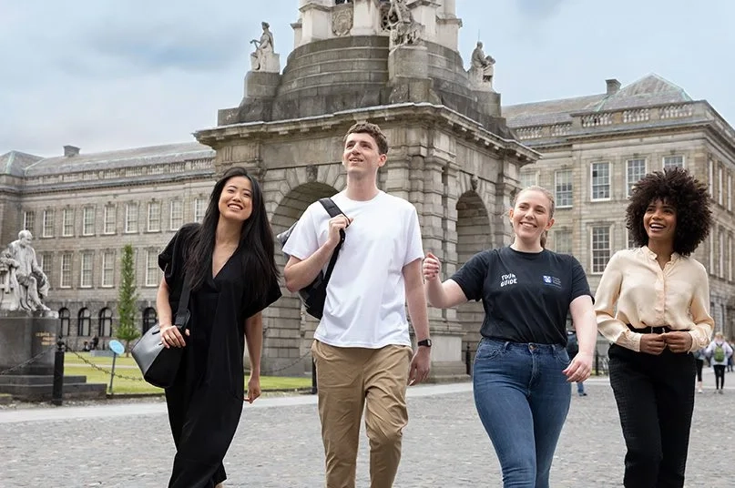 group of people walking and smiling in trinity college dublin campus