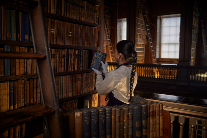 girl removing old books from library shelves