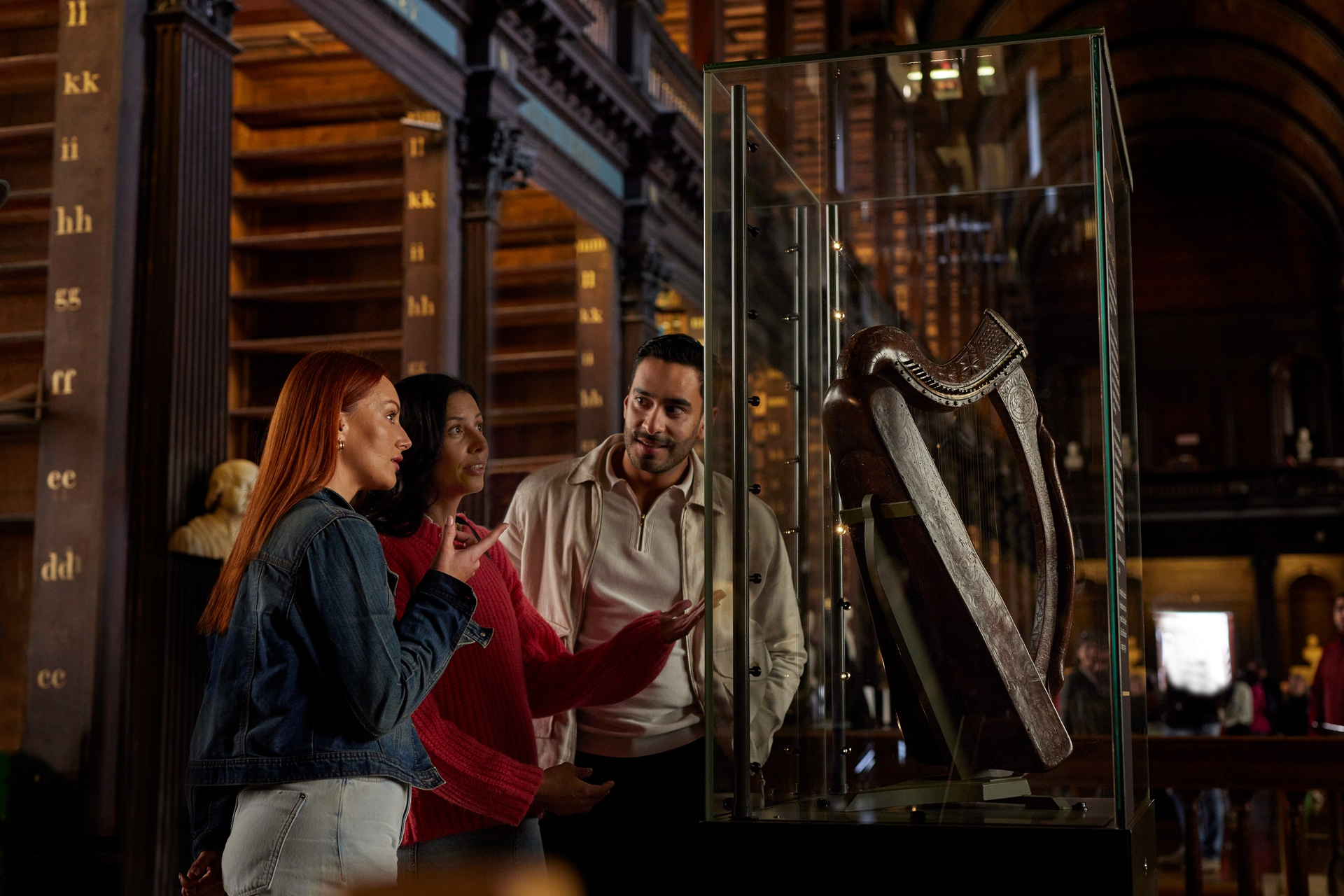 3 people looking at the Brian Boru harp in the Long Room