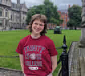 Tour guide standing in Trinity's Front Square with a lawn behind them.