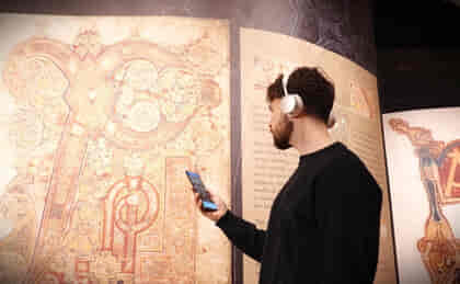 Man wearing earphones viewing the Book of Kells exhibition