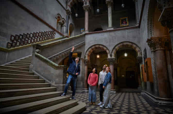 A tour guide with 3 people in Trinity's Museum Building.